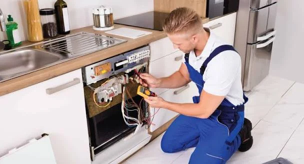 Technician testing wiring behind a dishwasher door panel