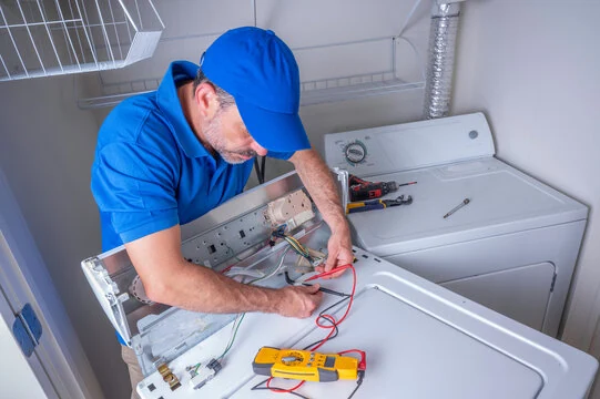 Technician testing electrical connections in laundry equipment