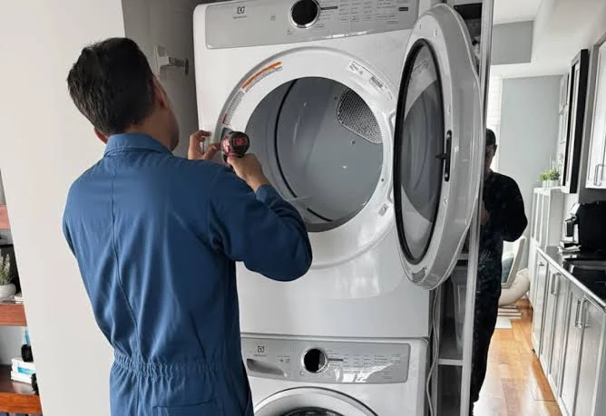 Technician inspecting the open door of a stacked laundry dryer